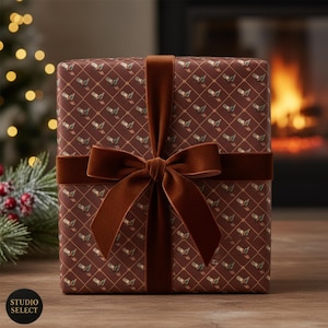 Puede incluir: Una caja de regalo envuelta con papel marrón estampado y una cinta y lazo de terciopelo marrón oscuro. El papel tiene un patrón repetido de pequeñas imágenes verdes y doradas sobre un fondo marrón. El lazo está centrado en la parte delantera de la caja.
