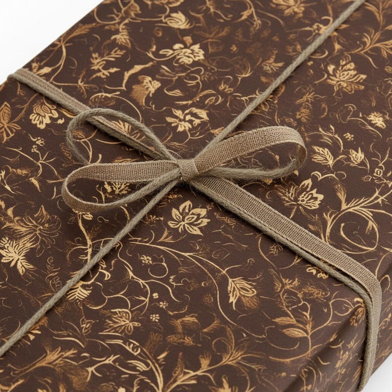 May include: A wrapped gift box with brown floral patterned paper and a tan ribbon tied in a bow. The paper has a gold floral design. The ribbon is wrapped around the box and tied in a bow on top.