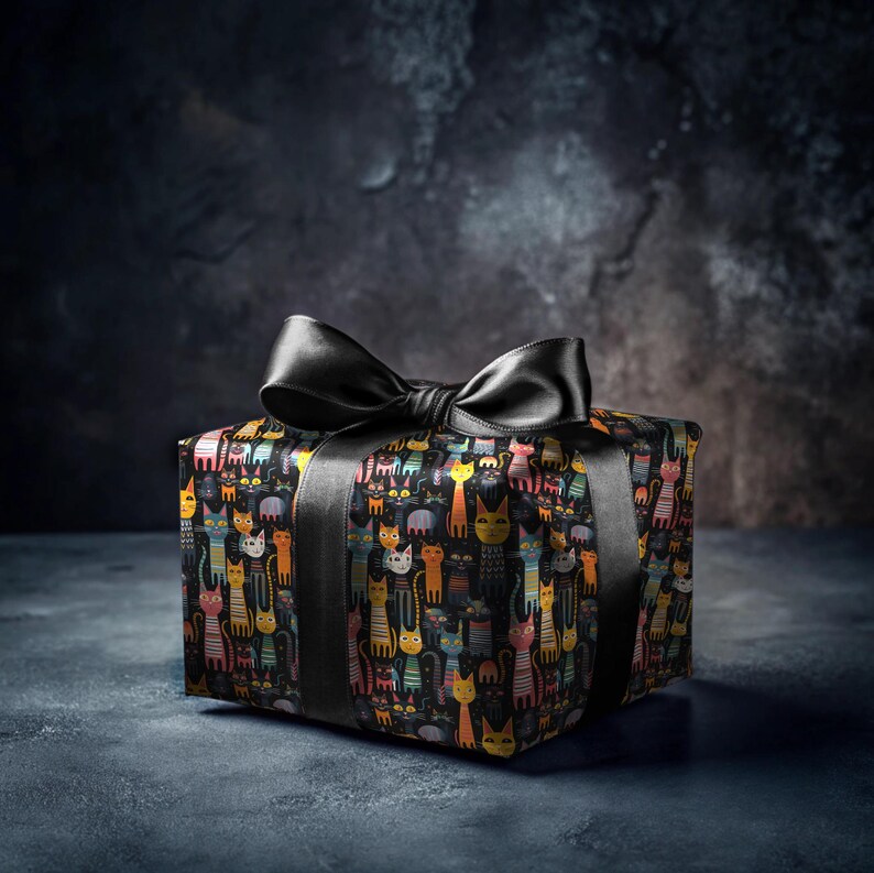 May include: A black gift box with a black satin ribbon tied in a bow. The box is wrapped in colorful patterned paper featuring a repeating design of cats.