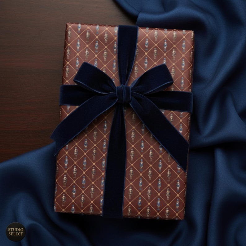 May include: A wrapped gift with brown paper featuring a repeating pattern of figures in blue and white. The gift is tied with a wide, navy blue velvet ribbon and bow. The background is a dark wood surface and navy blue fabric.
