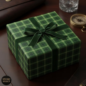 Puede incluir: Una caja de regalo envuelta en papel de cuadros verdes y una cinta de terciopelo verde oscuro. El lazo está centrado en la parte superior de la caja. La caja de regalo está sobre una superficie de madera marrón oscuro.