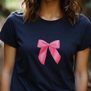 May include: A navy blue t-shirt with a pink bow design on the front.