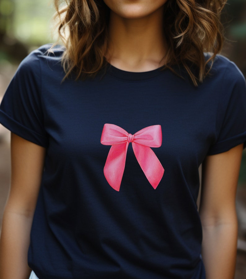 May include: A navy blue t-shirt with a pink bow design on the front.