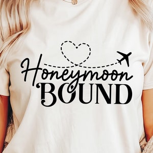May include: White t-shirt with black text that says "Honeymoon Bound" with a heart and airplane graphic.