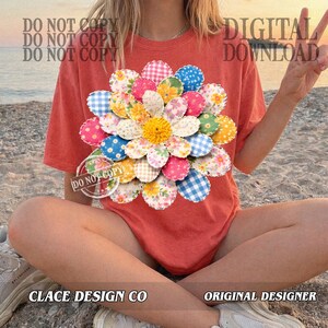 K&ouml;nnte beinhalten: Korallfarbenes T-Shirt mit einem gro&szlig;en Blumenmuster aus Stoff. Die Blume hat Bl&uuml;tenbl&auml;tter in Rosa, Blau, Gelb und Wei&szlig;. Der Text "DIGITAL DOWNLOAD" ist sichtbar. Der Text "CLACE DESIGN CO" ist ebenfalls sichtbar.