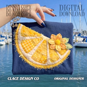 以下が含まれることがあります： 大きなアップリケのレモンスライスと花が付いた、濃いネイビーブルーのポーチ。レモンスライスは黄色と白で、ギンガム模様と質感のある皮が付いています。花はオレンジと黄色で、緑の葉が付いています。「DIGITAL DOWNLOAD」の文字が見えます。