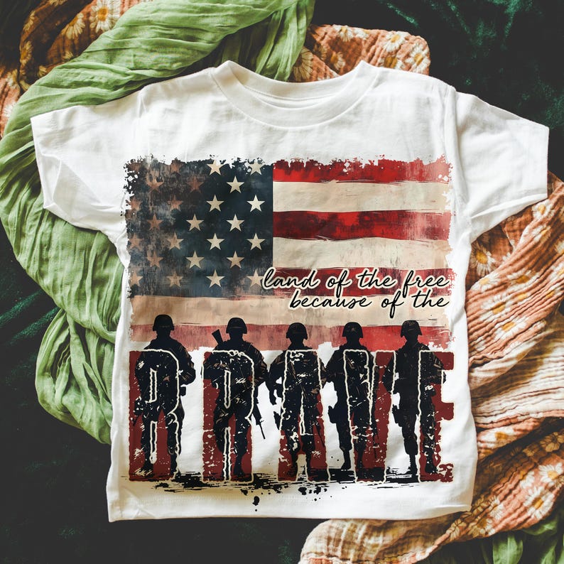 May include: White t-shirt with a distressed American flag design and the text "land of the free because of the BRAVE".
