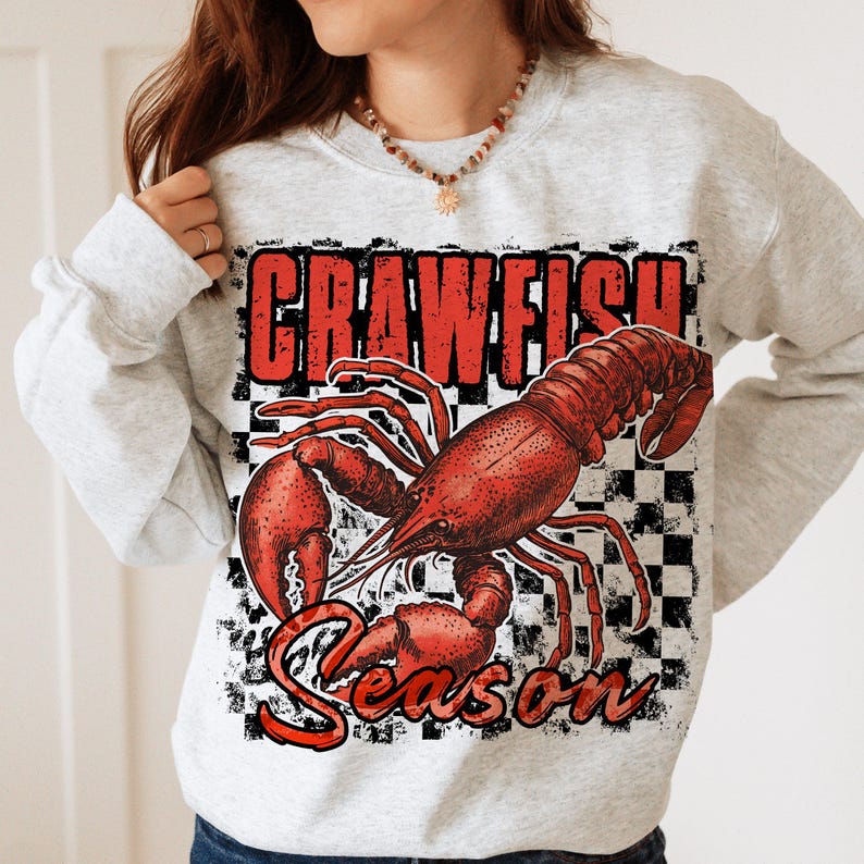 May include: A gray sweatshirt with a red crawfish illustration and the text "Crawfish Season" in black and white checkered background.