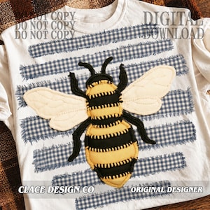 May include: A white t-shirt featuring a central graphic of a bee with yellow and black segments and cream-colored wings. The bee is layered over horizontal strips of blue and white gingham fabric with frayed edges. The text reads CLACE DESIGN CO.