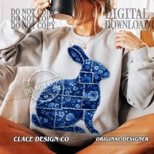 May include: A light grey sweatshirt with a blue floral patchwork rabbit design. The words "DIGITAL DOWNLOAD" and "CLACE DESIGN CO" are visible. The sweatshirt is a casual style.