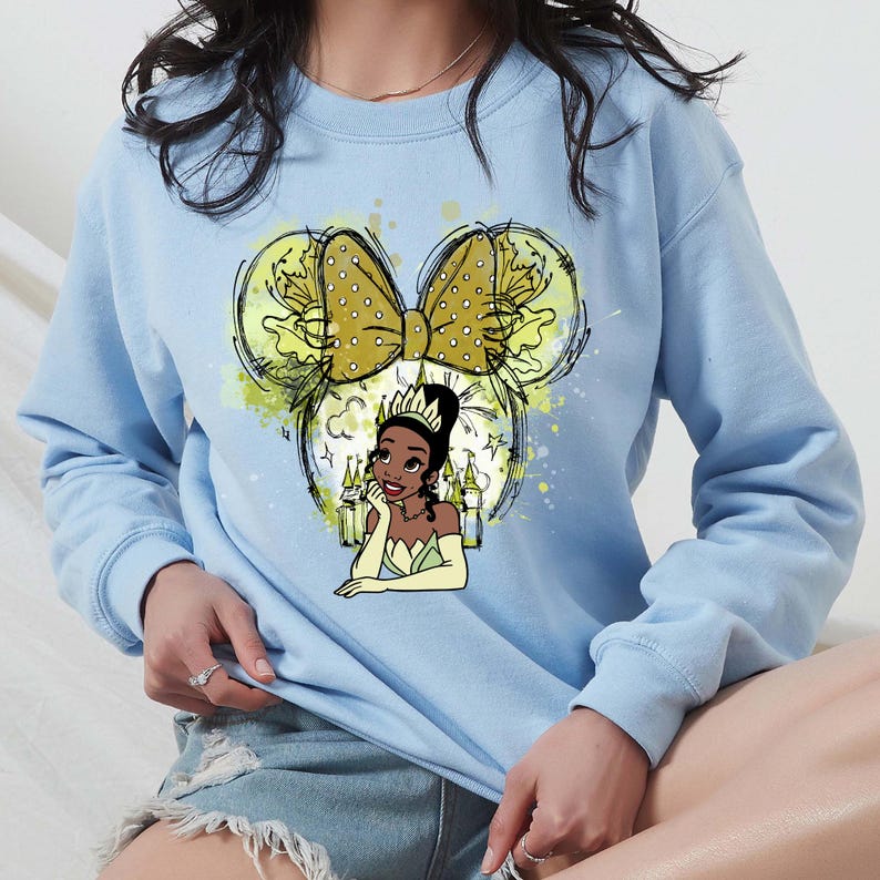 a woman sitting on a bed wearing a blue sweatshirt