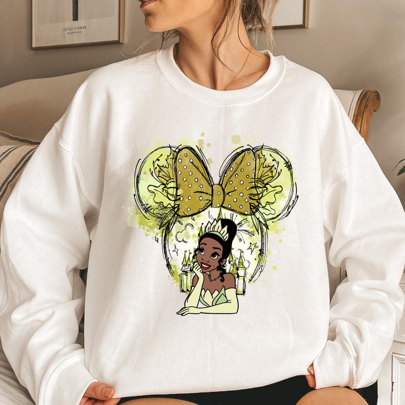 a woman sitting on a bed wearing a white sweatshirt