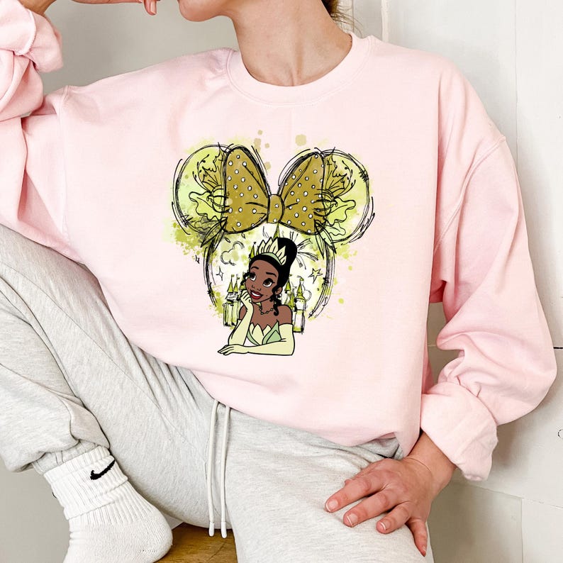 a woman sitting on a chair wearing a pink sweatshirt
