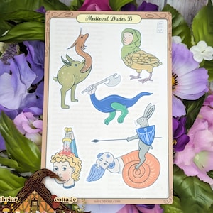 May include: A decorative card titled "Medieval Dudes B" featuring whimsical illustrations of medieval-themed creatures and figures. The card includes a green spotted creature, a blue dinosaur with an axe, and a rabbit riding a snail.