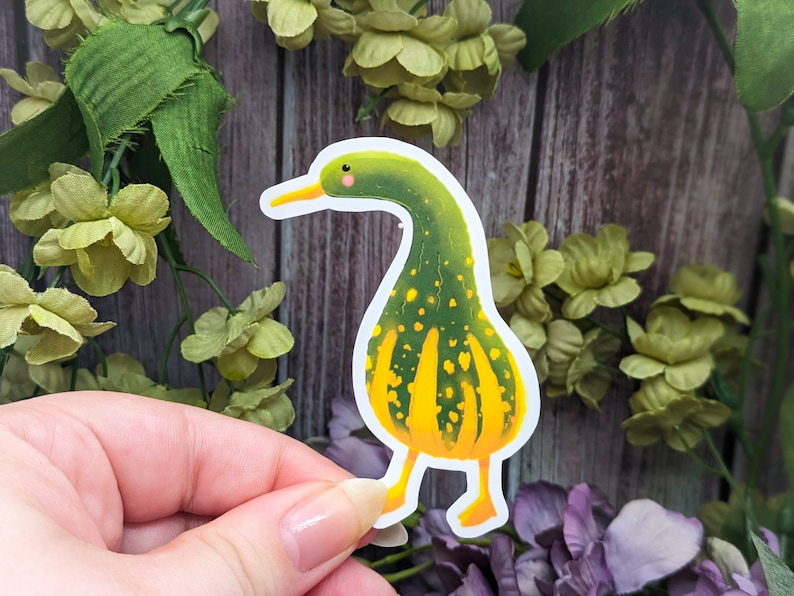 May include: A green and yellow gourd-shaped sticker with a duck head and feet. The sticker is on a white background.
