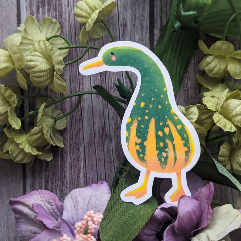May include: A green and yellow duck sticker with a white outline. The duck has a yellow beak and orange feet. The duck is on a white background.