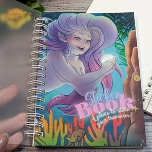 May include: Spiral-bound sticker book with a mermaid illustration, purple hair, and a glowing orb. The cover reads "Sticker Book: A place to store your treasures" against an underwater scene with coral and a turtle.