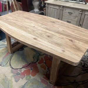 May include: A light brown wooden coffee table with a rectangular top and angled legs. The table is made of natural wood and has a smooth, unfinished surface. The table is approximately 122 cm long.