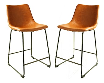 May include: Two brown leather bar stools with black metal frames. The seats have a stitched design and a curved back. The stools have a modern design and are set against a white background.