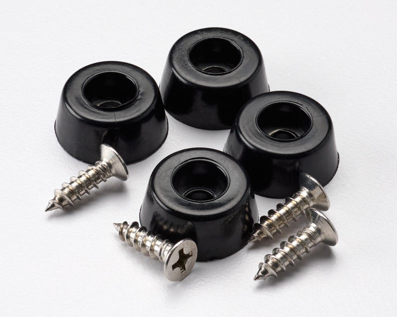 May include: Four black, circular, tapered rubber feet with a recessed center hole for mounting. Each foot is accompanied by a silver-colored metal screw with a flat head and a Phillips drive, designed for secure attachment to furniture or equipment.