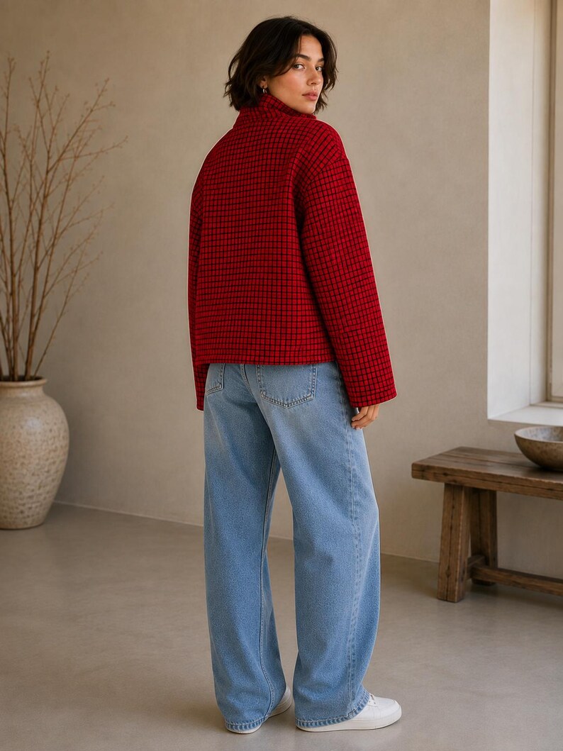 Puede incluir: Una chaqueta roja con patr&oacute;n de cuadr&iacute;cula negra y cuello alto, combinada con pantalones vaqueros de mezclilla azul claro y zapatillas blancas. La chaqueta presenta mangas largas y un dobladillo recto, mientras que los vaqueros tienen un corte holgado.