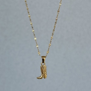 May include: A gold chain necklace with a small gold boot pendant.