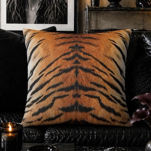 May include: A square throw pillow featuring a realistic orange and black tiger stripe pattern. The design displays a symmetrical arrangement of dark vertical stripes against a textured golden-orange background, mimicking the appearance of fur.