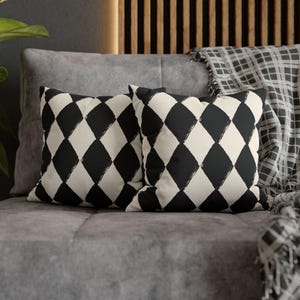 May include: Two decorative throw pillows with a black and white diamond pattern. The pillows are made of a soft, textured fabric and have a subtle sheen.