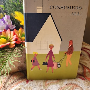 May include: A vintage book titled "Consumers All" with a mid-century illustration of a family and a house. The cover features a gray background, a black roof, and a green lawn. The family is depicted walking on the lawn.