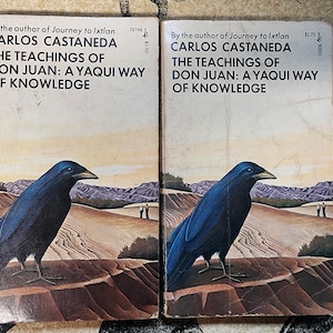 May include: Two identical paperback books titled The Teachings of Don Juan: A Yaqui Way of Knowledge by Carlos Castaneda. The covers feature a large dark blue crow in the foreground with a desert landscape and two small figures in the distance.