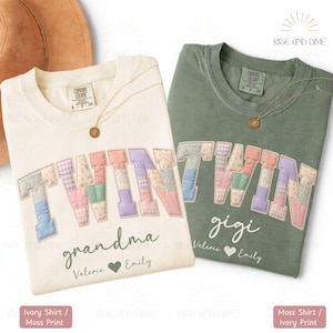May include: Two t-shirts, one ivory and one moss green, with the word "TWIN" in patchwork letters. The ivory shirt says "grandma" and the green shirt says "gigi". Both shirts have names and a heart below the word.