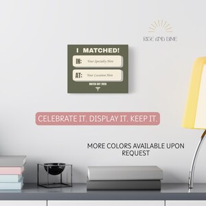 K&ouml;nnte beinhalten: Ein quadratisches, olivgr&uuml;nes Schild mit dem Text "I MATCHED!" und Feldern zum Ausf&uuml;llen von Fachgebiet und Standort. Darunter steht "MATCH DAY 2026" und "CELEBRATE IT. DISPLAY IT. KEEP IT."