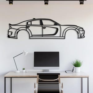May include: Black metal wall art of a car silhouette. The car is a side profile of a modern muscle car with a sleek design. The art is mounted on a white wall above a desk with a computer, lamp, and chair.