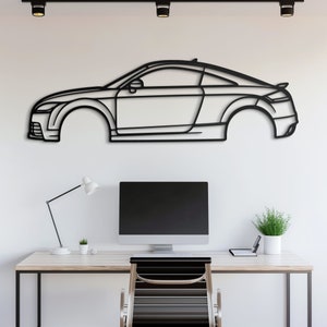 Puede incluir: Arte de pared de metal negro en forma de silueta de coche. El coche es un coupé con un diseño elegante. El arte está montado en una pared blanca sobre un escritorio con un ordenador, una lámpara y una silla.