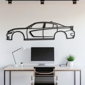 May include: Black metal outline of a Dodge Charger car silhouette mounted on a white wall above a desk with a computer, lamp, and chair.