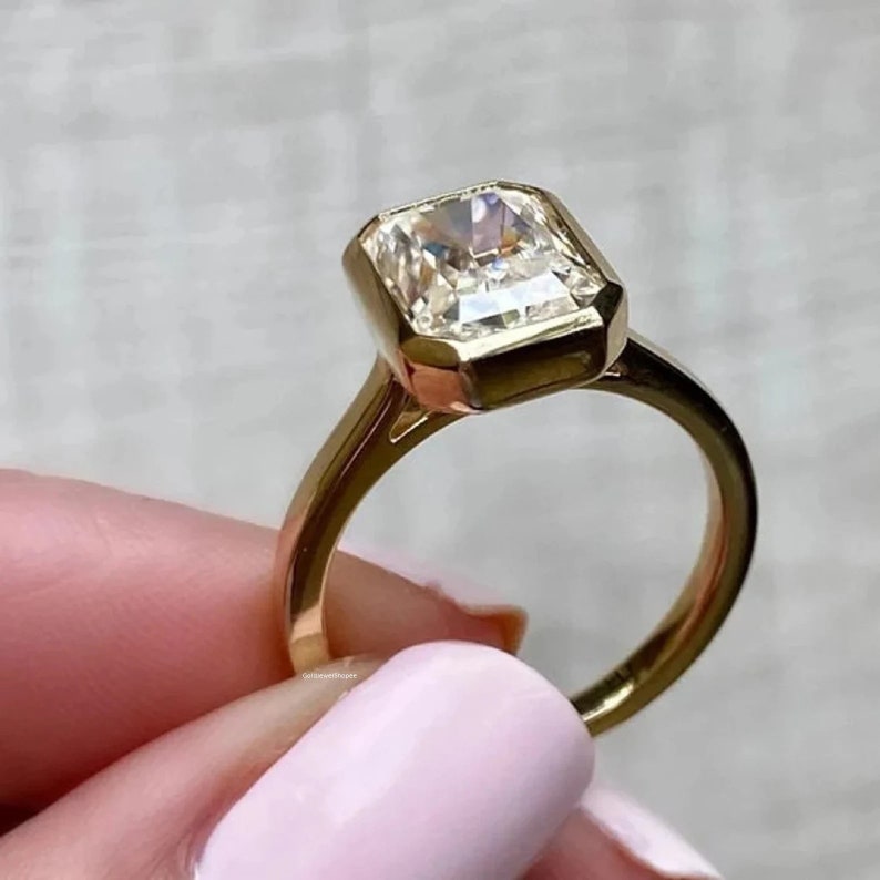 Pu&ograve; includere: Un anello d'oro con un grande diamante chiaro di forma quadrata. Il diamante &egrave; incastonato in una montatura a bezel, che gli conferisce un aspetto moderno ed elegante.