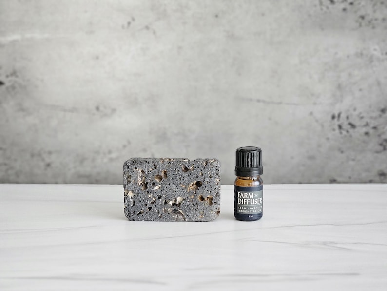 May include: A black lava rock diffuser with a small bottle of dark lavender essential oil. The bottle has a black label with the text "Farm Diffuser Dark Lavender Essential Oil 5ml".