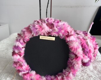 Kleine runde schwarze Tasche aus Kunstleder und rosa Fell.