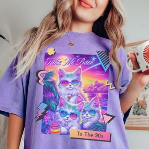 Puede incluir: Camiseta morada de gran tamaño con un estampado gráfico de tres gatos de dibujos animados con gafas de sol y el texto "Take Me Back To The 90s".
