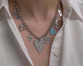 May include: Silver chain necklace with multiple charms, including a heart, a turtle, a crescent moon, an evil eye, and a charm that says "Love".