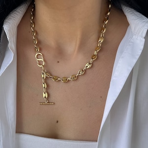 Puede incluir: Un collar de cadena de oro con cierre de palanca. La cadena está hecha de eslabones ovalados y tiene un aspecto delicado y femenino.