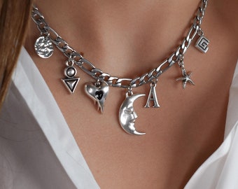 May include: A silver chain necklace with multiple charms, including a crescent moon, a heart, a star, a triangle, and a square. The charms are all silver and have a vintage look.