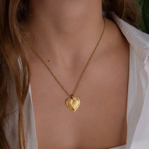 A delicate necklace in 18k gold plated stainless steel chain with a heart pendant. The heart length is 23mm. A unique handmade necklace with a small pearl. The perfect gift for someone you love.