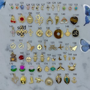 May include: Assortment of gold-tone charms with various designs, including a butterfly, a crescent moon, a cross, a key, a cherry, a sun, a clover, a horseshoe, an eye, a rainbow, a tiger's eye, a paw print, a star, a planet, a bee, a wave, a mountain, a lightning bolt, a bicycle, an aeroplane, a lock, a teddy bear, a mushroom, a word "Mom", a girl, a footprint, a crown, a butterfly, a key, a lock, a heart, a flower, a moon, a fish, a whale tail, a crab, a cactus, a cowboy hat, a boot, a horse, a pearl, a seahorse, and an anchor.