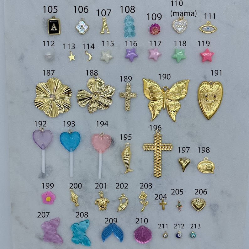 May include: An assortment of colourful charms and pendants, including hearts, stars, butterflies, crosses, fish, seashells, and a flower. The charms are made of gold, silver, and plastic. The charms are numbered 105 through 213.