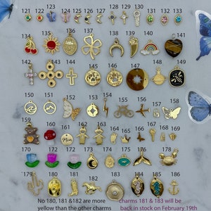 May include: A collection of 186 gold-tone charms, including a variety of shapes, symbols, and designs. The charms are arranged in rows on a white background. The charms are numbered from 121 to 186. The text "No 180, 181 &182 are more yellow than the other charms" and "Charms 181 & 183 will be back in stock on February 19th" is printed below the charms.