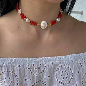 May include: A red coral and white pearl choker necklace with a gold shell pendant.