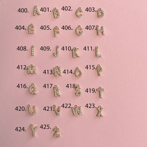 May include: A set of 26 gold-tone letter charms, each adorned with clear sparkling rhinestones. The charms are arranged in alphabetical order from A to Z, with each letter numbered sequentially from 400 to 425.