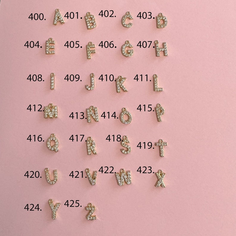 May include: A set of 26 gold-tone letter charms, each adorned with clear sparkling rhinestones. The charms are arranged in alphabetical order from A to Z, with each letter numbered sequentially from 400 to 425.