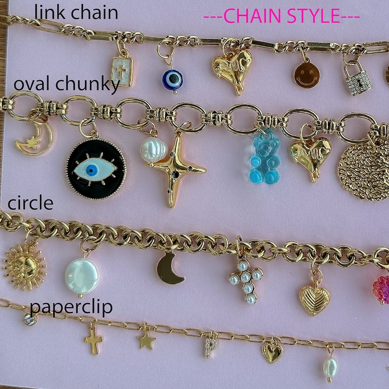 May include: Four gold chains with different link styles and charms. The top chain has a link chain style and charms including a cross, an evil eye, a heart, a smiley face, and a padlock. The second chain has an oval chunky link style and charms including a crescent moon, an evil eye, a pearl, a star, a gummy bear, a heart, and a circle. The third chain has a circle link style and charms including a sun, a pearl, a crescent moon, a cross with pearls, a heart, and a pink flower. The fourth chain has a paperclip link style and charms including a cross, a star, a letter P, a heart, and a pearl.